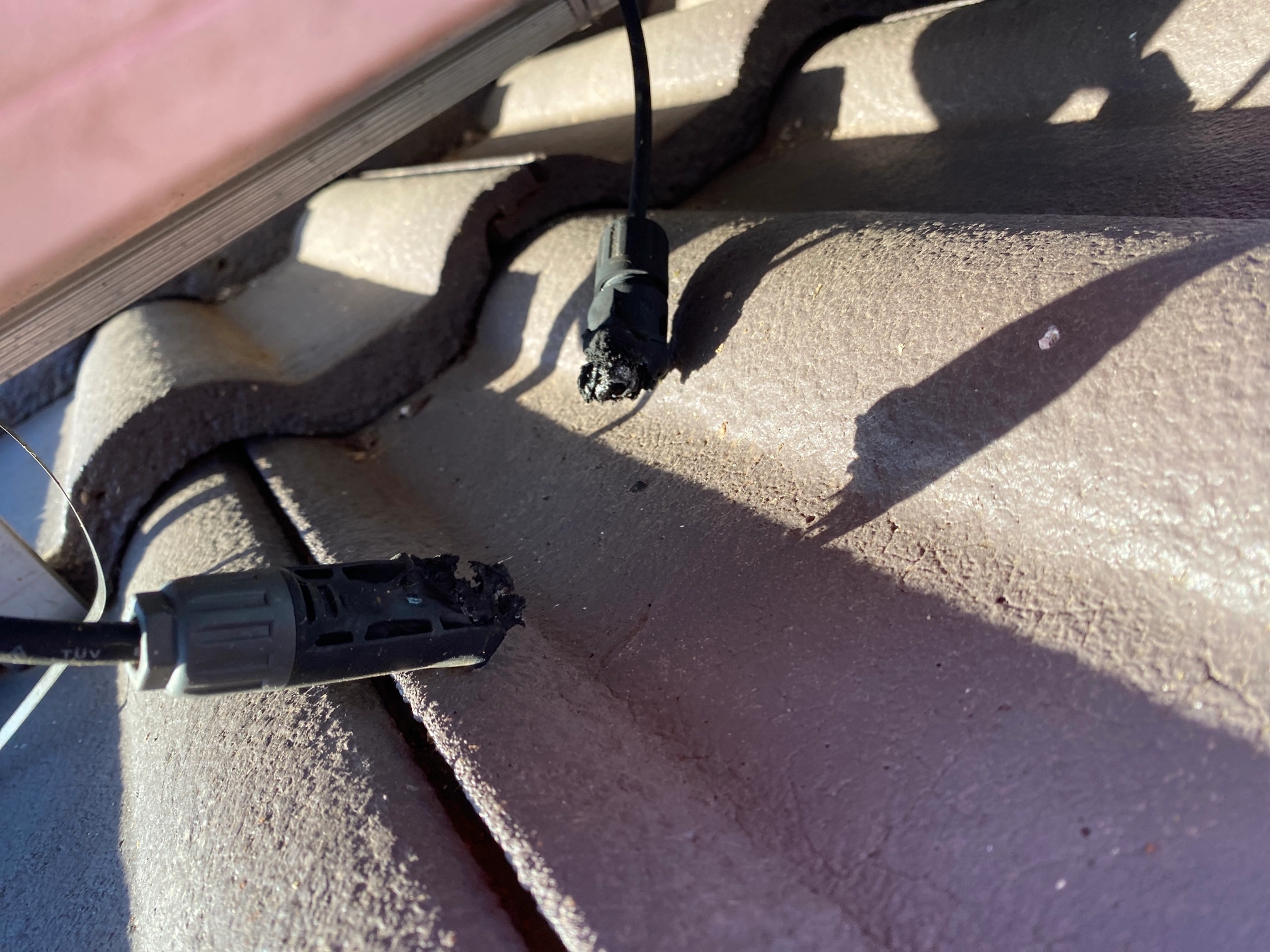 Burnt MC4 solar connectors under a rooftop panel, found during an NG Elec solar repair inspection