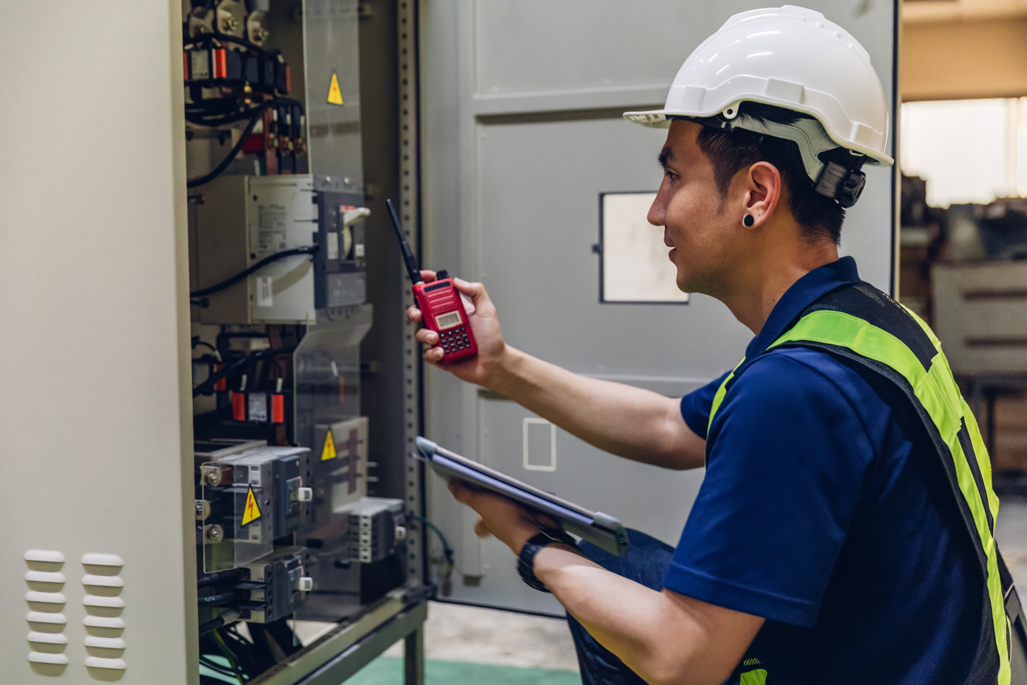 Electrician inspecting a commercial switchboard during scheduled electrical maintenance
