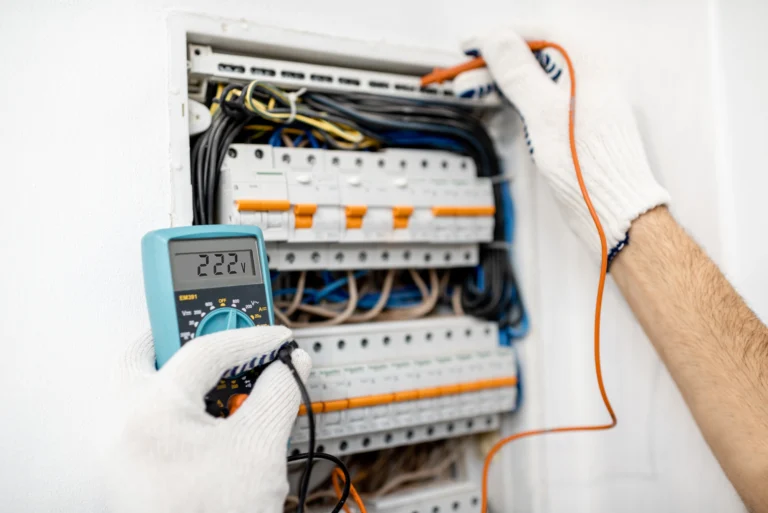 Electrician testing circuit breakers in a switchboard with a multimeter